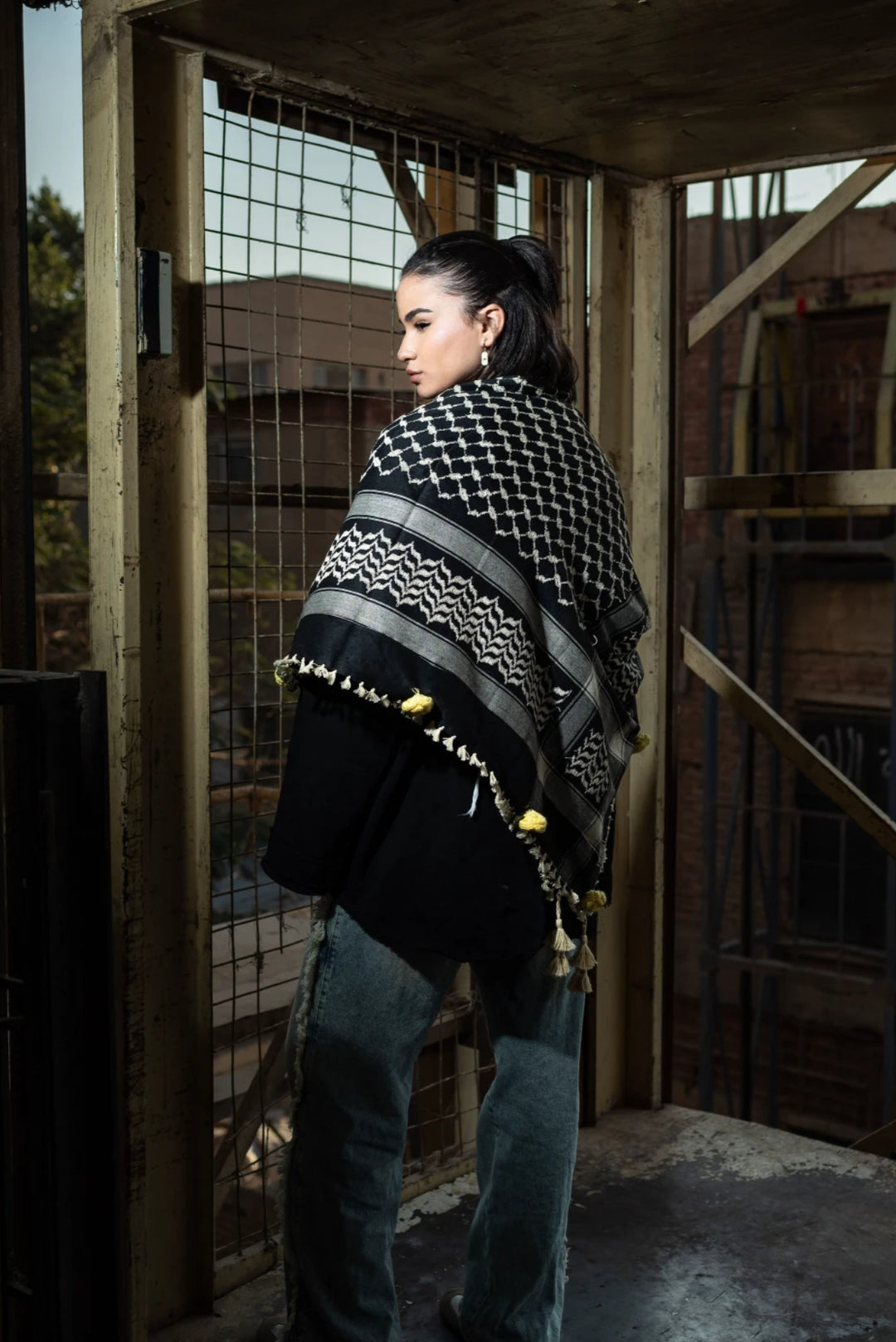 Person wearing a patterned shawl in an industrial setting